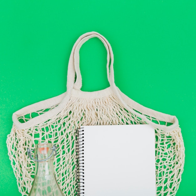 Vue de dessus du sac réutilisable avec carnet et bouteille en verre