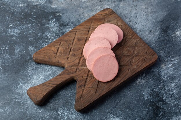 Vue de dessus du salami frais tranché sur une planche à découper en bois.