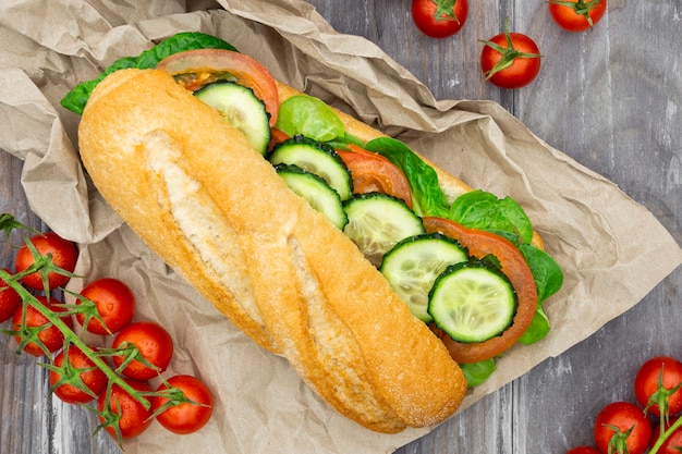 Photo gratuite vue de dessus du sandwich sur papier avec des tomates et des tranches de concombre