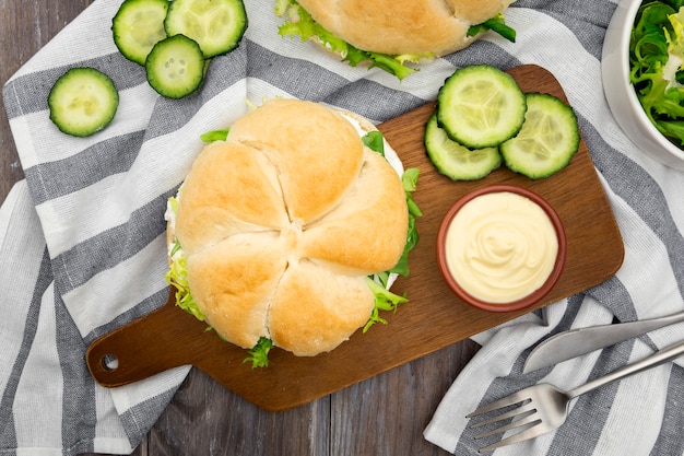 Photo gratuite vue de dessus du sandwich sur une planche à découper avec de la mayonnaise et des tranches de concombre