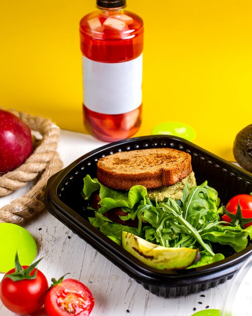 Vue de dessus du sandwich végétalien avec avocat et tomates dans une boîte de livraison