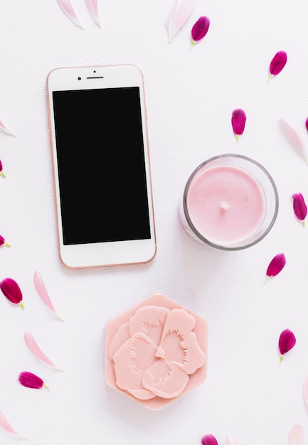 Une vue de dessus du savon en forme de fleur; bougie et smartphone décorés de pétales