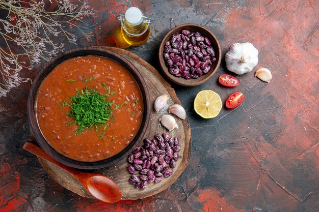 Vue de dessus du savon de tomate haricots ail cuillère sur planche à découper en bois et bouteille d'huile citron