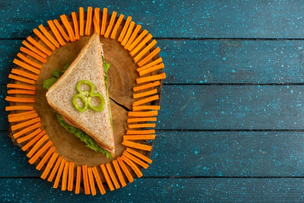 Vue de dessus du savoureux sandwich avec salade verte jambon et tomates comme garniture sur la surface rustique bleue