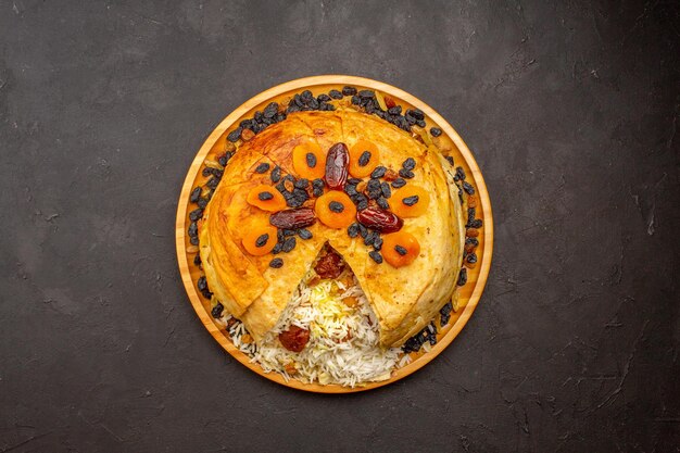 Vue de dessus du savoureux shakh plov avec des raisins secs et des abricots secs sur la surface sombre