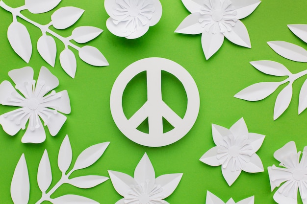 Photo gratuite vue de dessus du signe de paix papier avec des feuilles et des fleurs