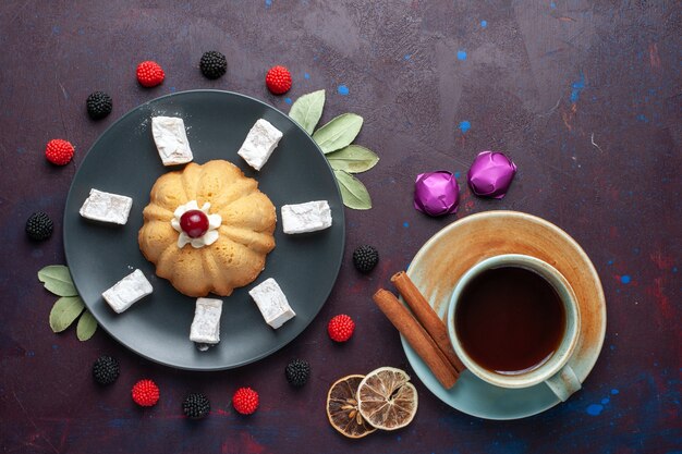 Vue de dessus du sucre en poudre bonbons délicieux nougat avec gâteau et thé de baies de confiture sur une surface sombre