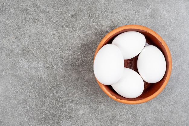 Photo gratuite vue de dessus du tas d'oeufs dans un bol potier sur table grise.