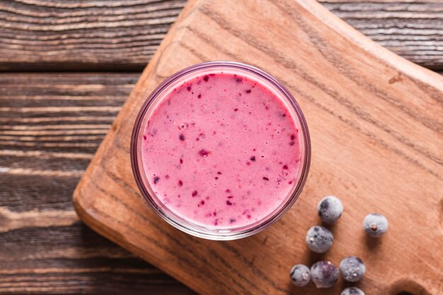 Vue de dessus du verre à smoothie sur une planche à découper avec des bleuets