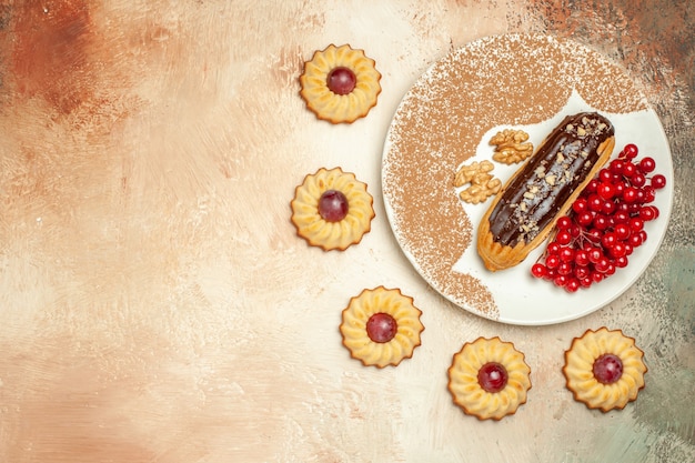 Vue de dessus eclair délicieux avec des baies rouges et des biscuits sur la table légère dessert gâteau sucré