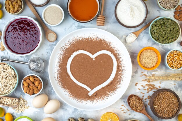 Vue de dessus empreinte de coeur dans du cacao en poudre sur des bols en assiette blanche avec d'autres aliments sur la table