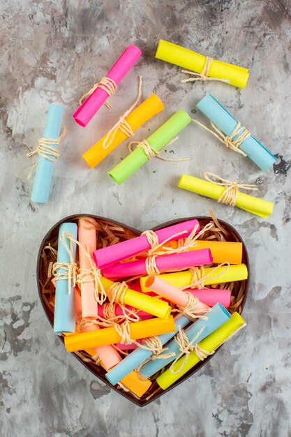 Vue de dessus enroulé des notes autocollantes colorées dans une boîte en forme de coeur sur la table