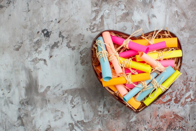 Vue de dessus enroulé des notes autocollantes colorées dans une boîte en forme de coeur sur une table avec