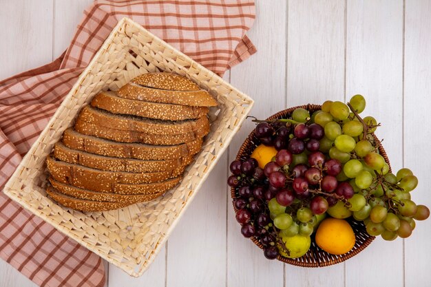 Vue de dessus de l'épi semé brun en tranches dans le panier sur tissu à carreaux et panier de fruits comme nectacot de raisin pluot sur fond de bois