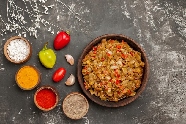 Vue de dessus des épices et assiette de haricots verts et tomates épices colorées sur la table sombre