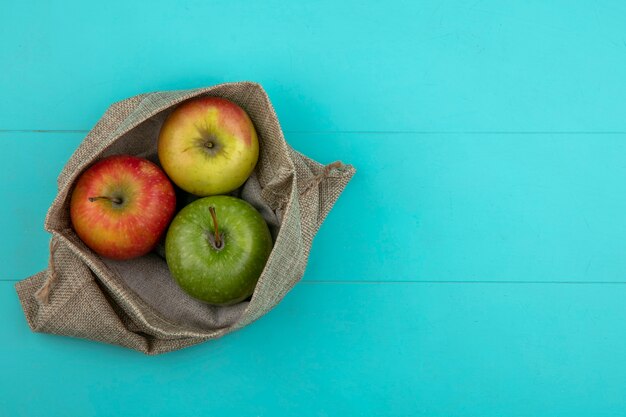 Vue de dessus de l'espace de copie de pommes colorées dans un sac de jute sur un fond bleu clair