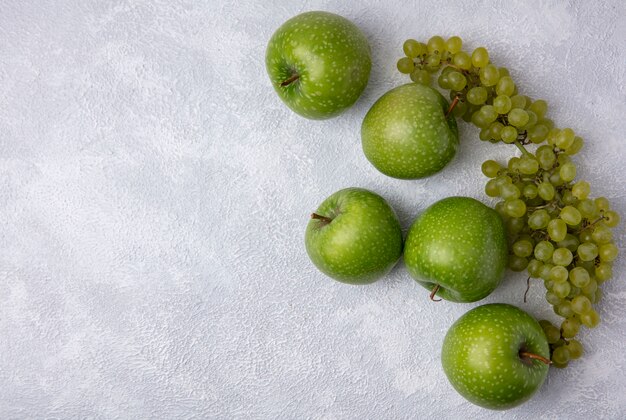 Vue de dessus espace copie pommes vertes avec des raisins verts sur fond blanc