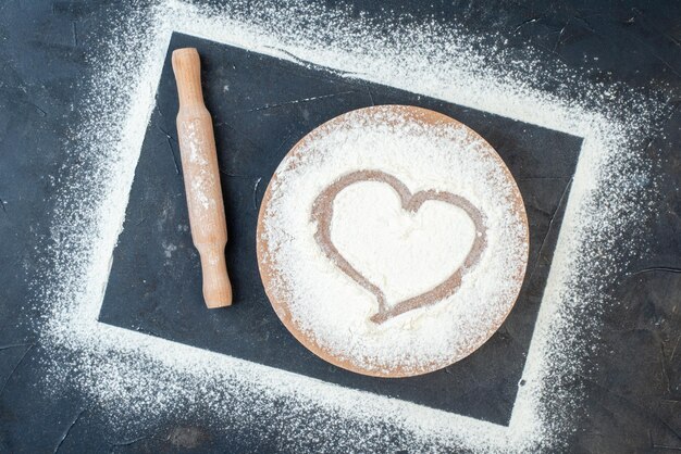 Vue de dessus farine blanche en forme de coeur sur fond gris farine biscuit pâte couleur repas cuire au four oeuf