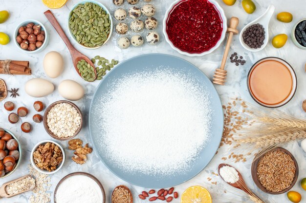 Vue de dessus de la farine blanche à l'intérieur de l'assiette avec des graines de noix et des œufs sur une pâte blanche cuire de la gelée de noix de photo de couleur alimentaire