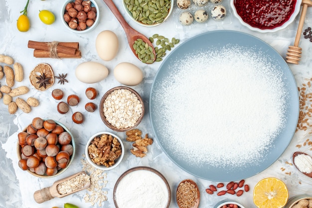 Vue de dessus de la farine blanche à l'intérieur de la plaque avec des graines de noix et des œufs sur une pâte blanche cuire de la gelée de noix de couleur alimentaire