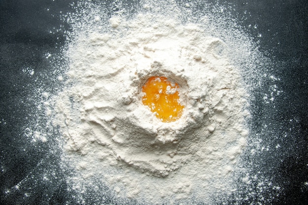 Vue de dessus de la farine blanche mélangée avec des œufs sur le fond sombre travail de pâtisserie gâteau aux œufs tarte boulangerie travailleur cuisine