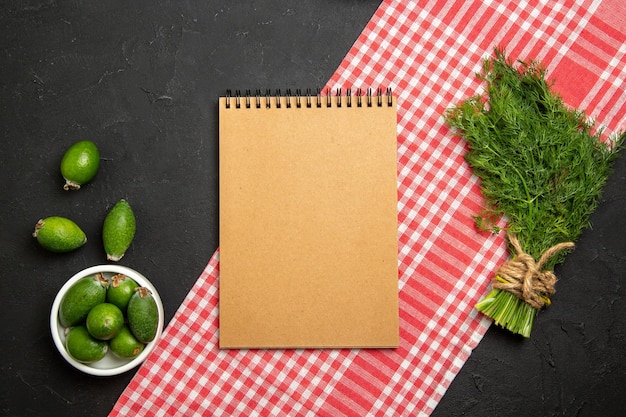 Vue de dessus feijoa frais avec des verts et un bloc-notes sur une surface sombre fruit vert vert frais