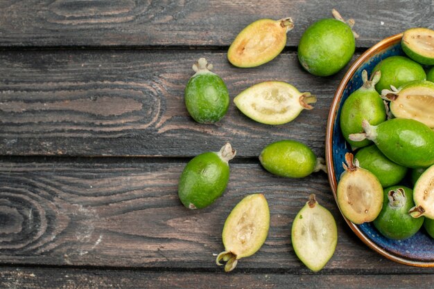 Vue de dessus des feijoas verts frais à l'intérieur de la plaque sur un bureau rustique en bois jus de photo couleur jus mûr aigre espace libre