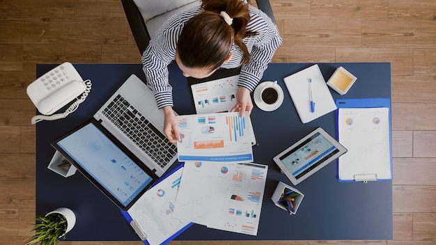 Vue de dessus d'une femme d'affaires assise à une table de bureau vérifiant les documents de comptabilité financière