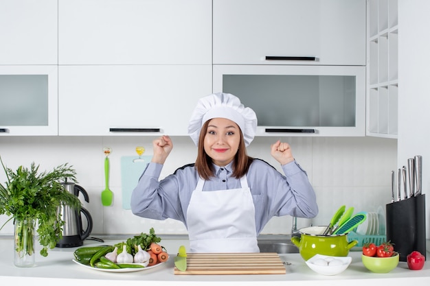 Vue de dessus d'une femme chef heureuse et de légumes frais avec du matériel de cuisine et dans la cuisine blanche