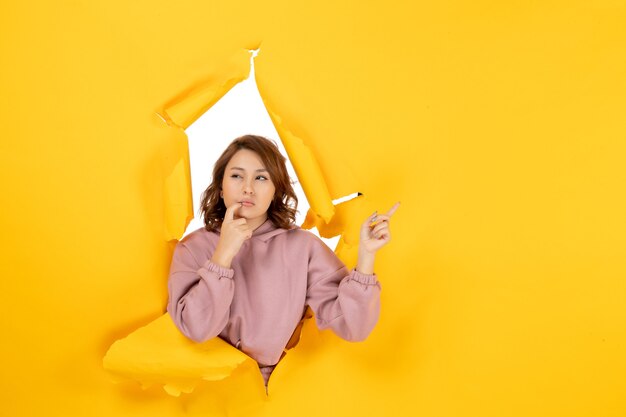 Vue de dessus d'une femme confuse pointant quelque chose et de l'espace libre sur une déchirure jaune