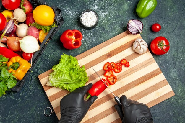 Vue de dessus femme cuisinier coupant du piment rouge sur la surface grise