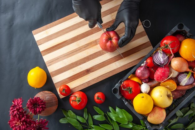 Vue de dessus femme cuisinier coupe pomme sur la surface sombre