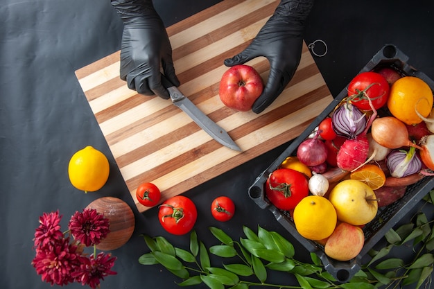 Vue de dessus femme cuisinier coupe pomme sur la surface sombre