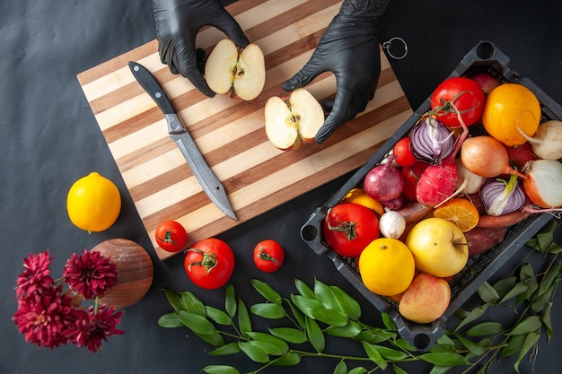 Vue de dessus femme cuisinier coupe pomme sur la surface sombre