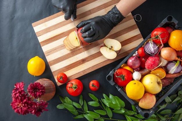 Vue de dessus femme cuisinier coupe pomme sur la surface sombre