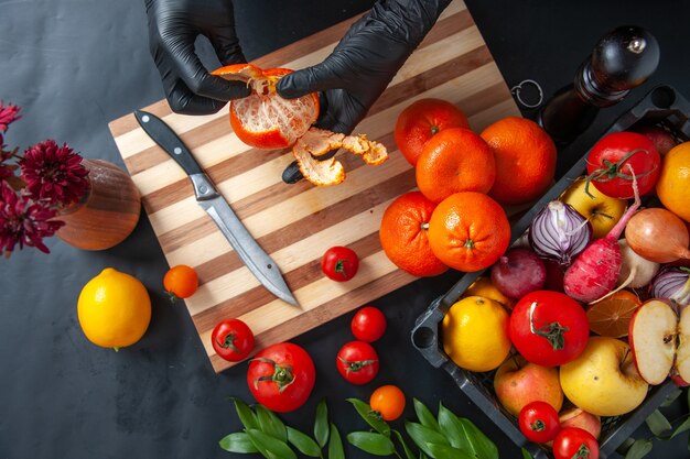 Vue de dessus femme cuisinier nettoyant les mandarines sur la surface sombre