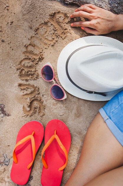 Vue de dessus de femme avec des éléments d&#39;été et d&#39;écriture dans le sable