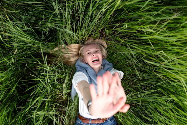 Vue de dessus d'une femme heureuse posant dans l'herbe