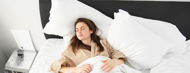 Photo gratuite vue de dessus d'une femme magnifique en pyjama dormant au lit avec les yeux fermés se relaxant à l'hôtel