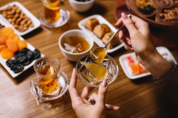 Vue de dessus femme mange de la confiture de pastèque avec un verre de thé