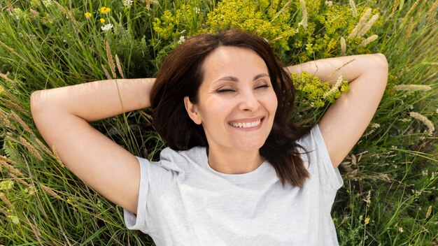 Vue de dessus de la femme posant dans l'herbe à l'extérieur