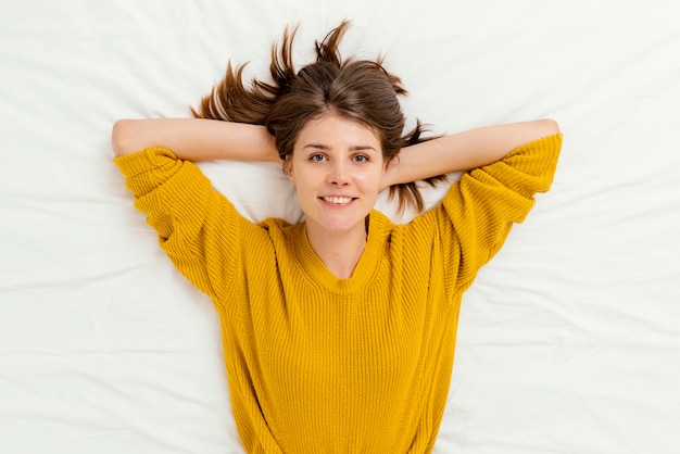 Vue de dessus femme pose dans son lit