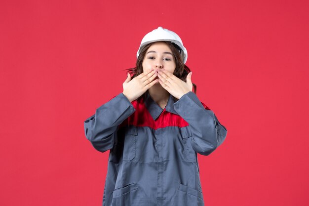 Vue de dessus d'une femme souriante en uniforme avec un casque et faisant un geste de baiser sur fond rouge isolé