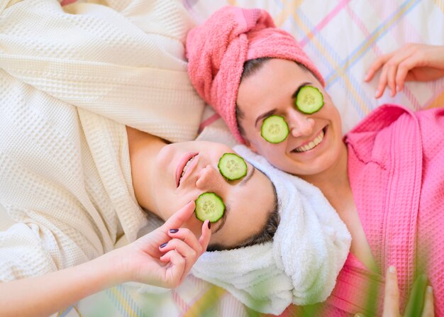 Vue de dessus des femmes souriantes avec des tranches de concombre sur les yeux