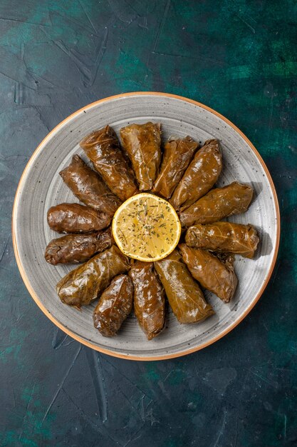 Vue de dessus feuille dolma délicieux repas de viande orientale roulé à l'intérieur des feuilles vertes sur le bureau bleu foncé repas de viande nourriture dîner légumes santé calorie