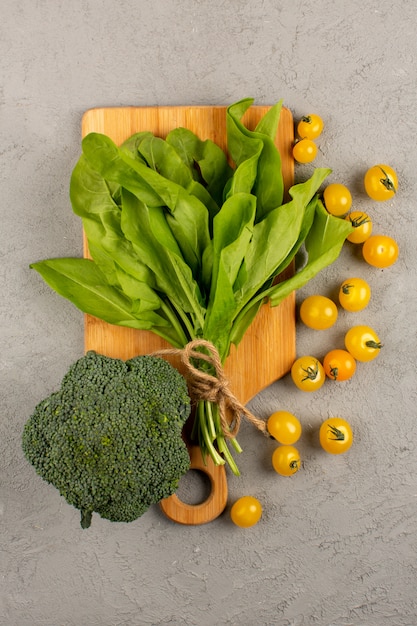 Vue De Dessus Des Feuilles De Brocoli Vert Avec Des Tomates Jaunes Sur Le Fond Gris