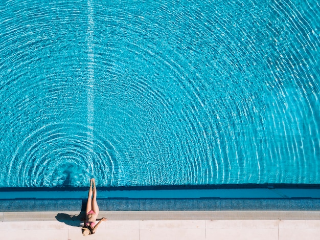 Vue de dessus d&#39;une fille se détendre à côté de la piscine