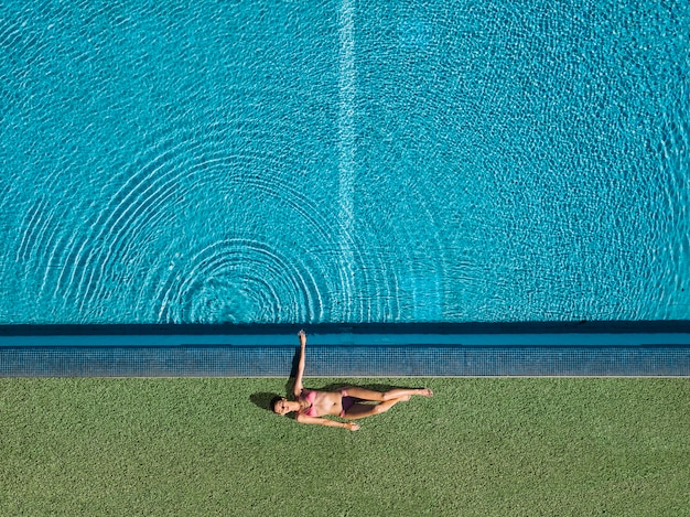 Vue de dessus d'une fille se détendre à côté de la piscine