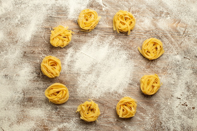 Photo gratuite vue de dessus de la fleur de pâtes de pâte crue formée avec de la farine sur fond de bois pâte alimentaire repas pâtes