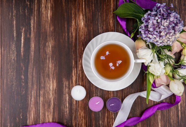 Vue de dessus de fleurs fraîches comme les roses tulipes gardenzia avec une tasse de thé sur un fond en bois avec espace copie